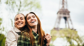 gay couple hugging in front of Eiffel Tower in Paris