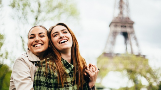 gay couple hugging in front of Eiffel Tower in Paris