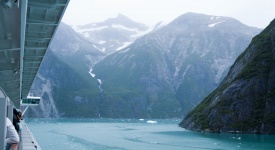 Near vertical mountain slopes carved by glaciers. The cold blue green waters of Tracy Arm Fjord in Alaska as viewed from a cruise ship.