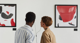 two people looking at art sharing a headphones